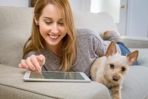 Woman on couch with puppy using ipad